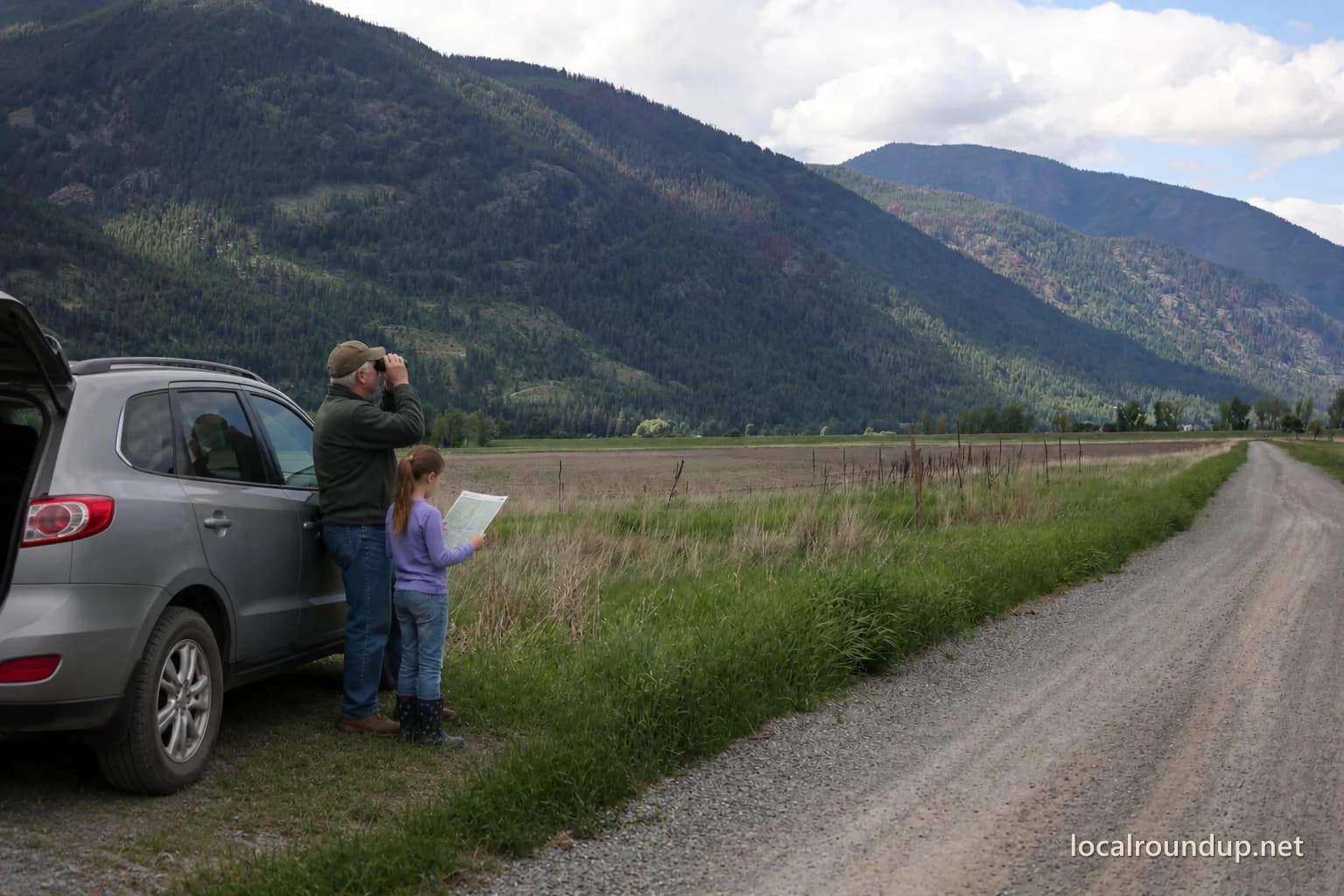A grandfather and child using binoculars beside the Kootenai refuge auto-tour road