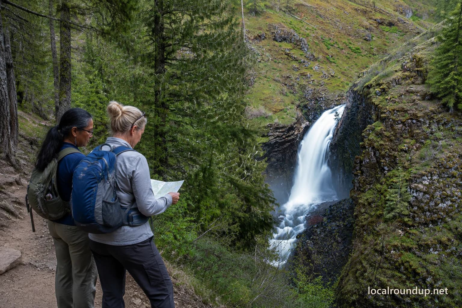 Two hikers checking a trail map near Elk Creek Falls